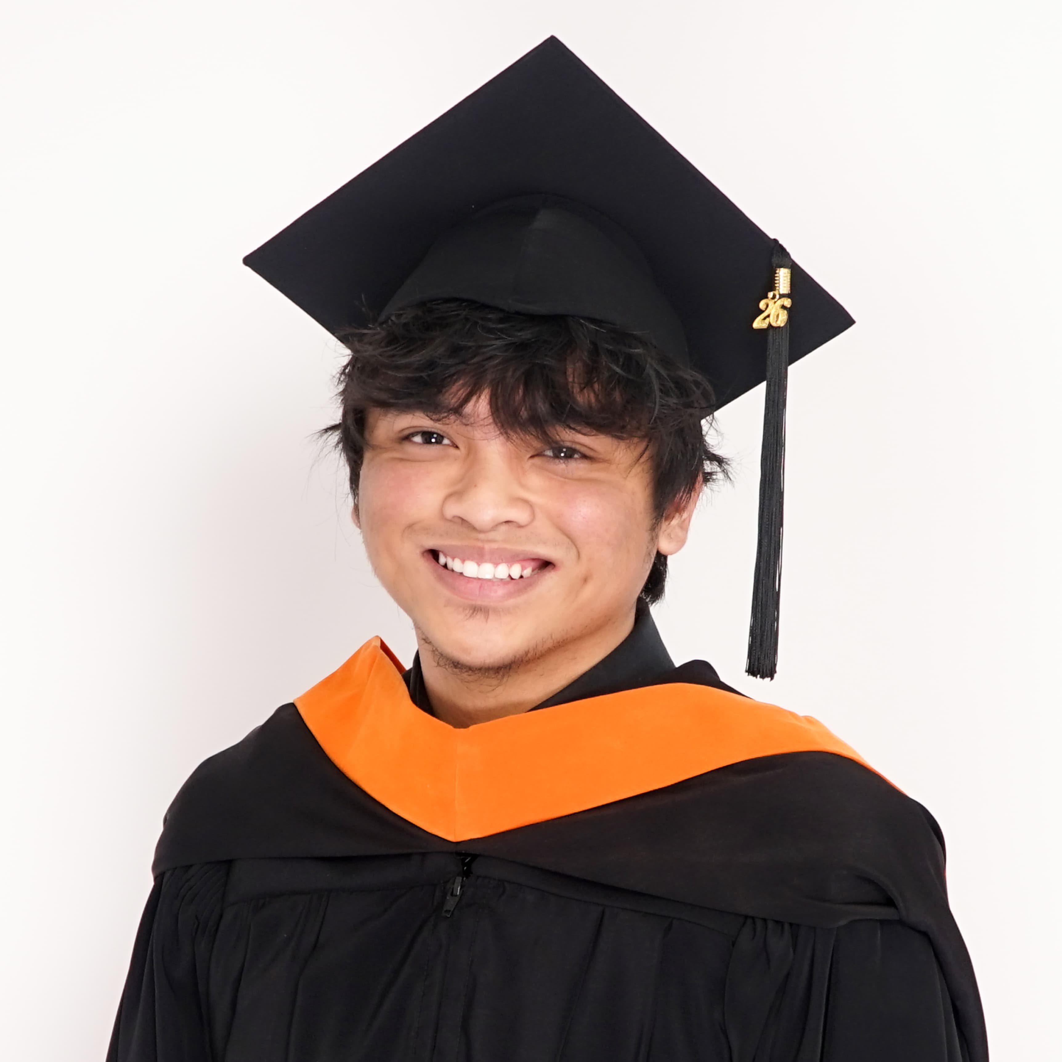 Graduation portrait in cap, gown, and orange stole, the year's tassel charm hanging beside my face
